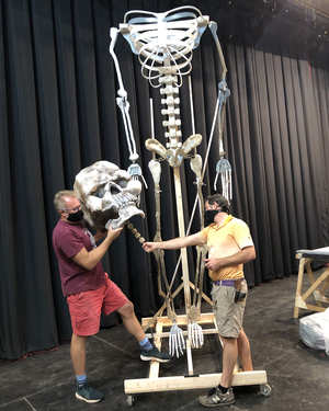 Two people work on a skeleton decoration
